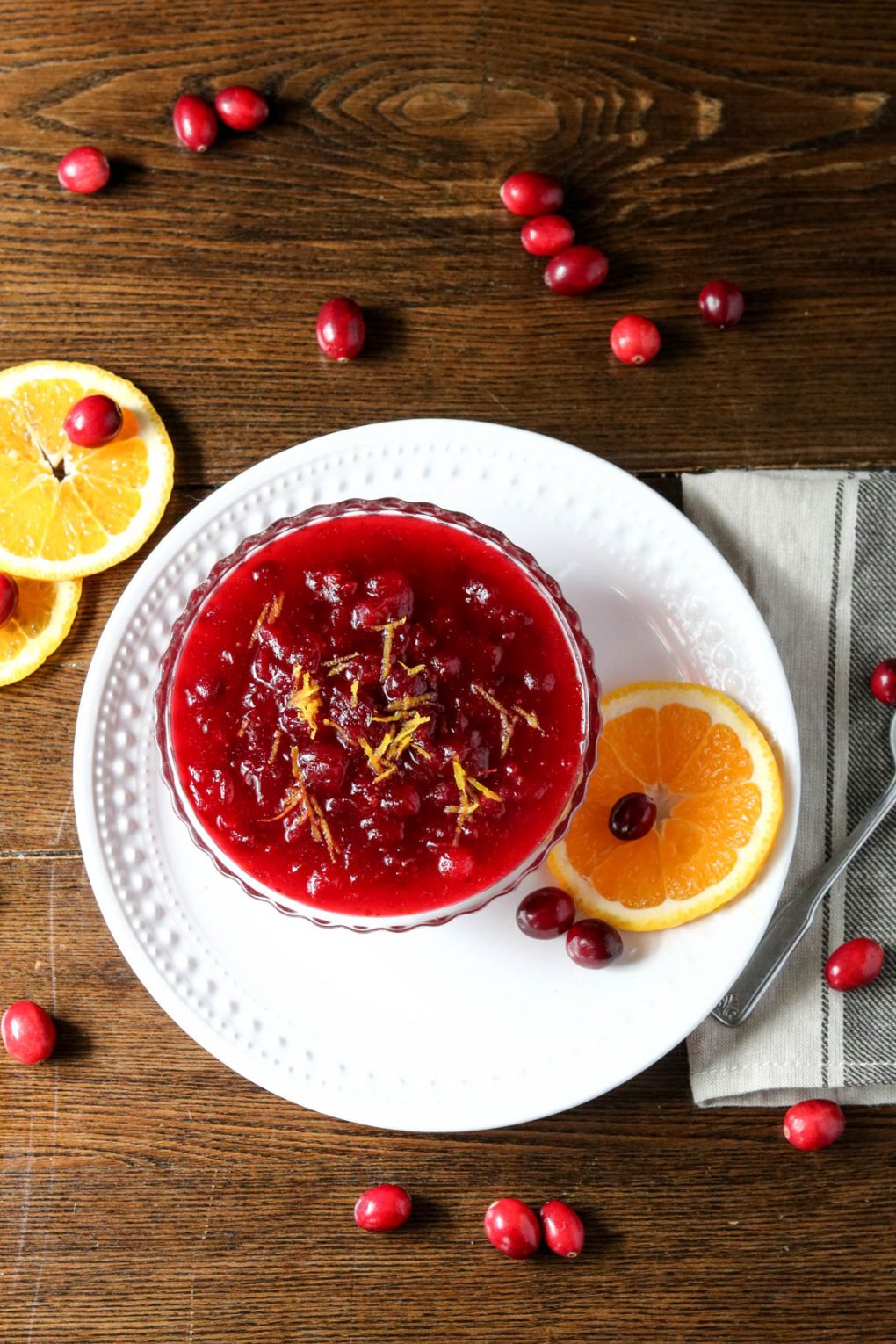a bowl of orange cranberry sauce garnished with fresh cranberries and orange slices